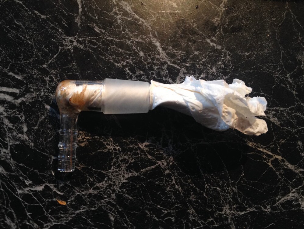 Ein Glas-Winkelstück eines Arizer Vaporizers, das mit einem Stück Küchenpapier gereinigt wird.