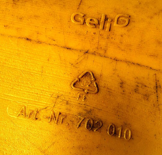Nahaufnahme der Unterseite einer gelben Gießkanne mit eingeprägtem Geli-Logo, Recycling-Code 02 (PE) und Artikelnummer 702 010.