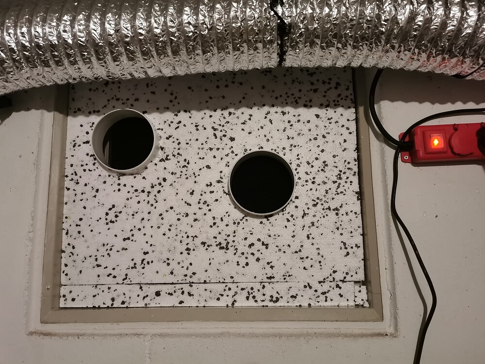 Selbstgebaute Fensterabdichtung aus Styropor mit zwei Abluftflanschen für ein Grow-Setup.